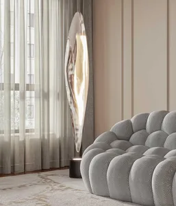 A modern minimalist interior featuring a metallic floor lamp and a textured, tufted sofa against a beige wall.