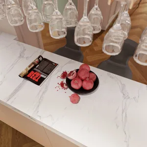 Top view of a modern kitchen interior with marble countertop, fresh pomegranates, and wine glasses hanging above.