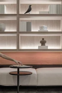A modern living room featuring a wooden shelving unit filled with books and decorative items.