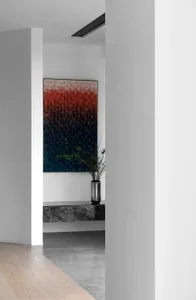 Modern lobby featuring marble columns, concrete floor, and a large minimalist painting on the wall.
