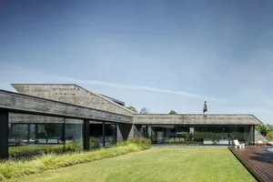 Modern residential house with concrete exterior, glass windows, and a spacious patio.
