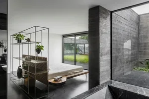 A minimalist bedroom featuring a concrete wall and a bed with a wooden frame.