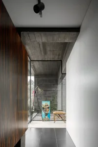 Modern entryway featuring a concrete ceiling, wooden flooring, and a glass and metal bench.