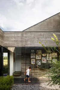 Modern concrete building exterior with glass doors and framed photographs on a wall.