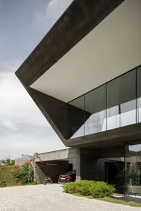 A modern house with a concrete structure and large glass windows.