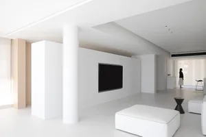 現代簡約客廳，純白牆面、家具與天花板。包含一面白牆上的平面電視與一