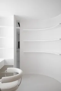 A minimalist white interior design space featuring a circular table and a white chair.