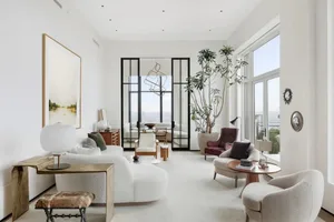 Modern minimalist living room with white furniture, large windows, and a potted plant.