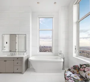 Modern bathroom with marble tiles and large windows overlooking a cityscape.
