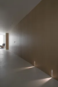 Modern minimalist corridor featuring wood-paneled walls, minimal lighting, and a quiet, unobtrusive atmosphere.