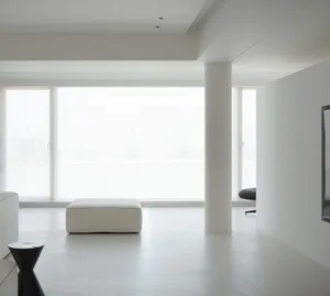 A minimalist living room with white concrete flooring and furniture.