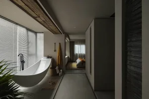 Modern minimalist bathroom with a freestanding bathtub, concrete walls, and yellow accents.