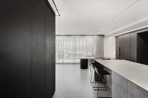 A modern minimalist kitchen with concrete countertops and dark cabinetry.