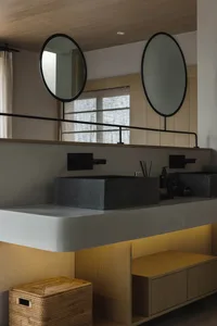 A modern bathroom featuring concrete sinks and wooden cabinets.