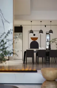 A modern dining room with a table and chairs surrounded by geometric shapes and hanging pendant lights.
