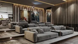 A modern entertainment room featuring plush grey sofas and large movie posters.