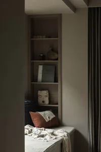 A modern bookshelf featuring decorative items and a cozy bench seat.