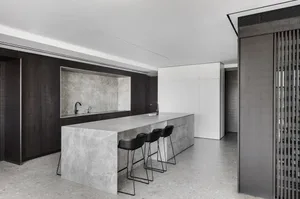 A modern kitchen with a marble island and concrete flooring.