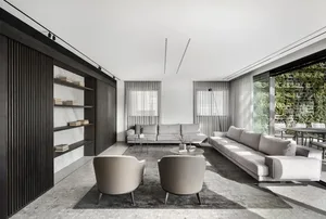 A modern living room with a minimalist design, featuring grey sofas, marble accents, and concrete flooring.