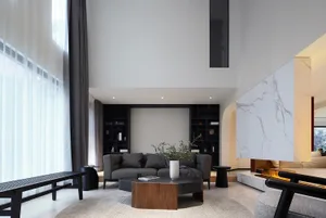 A modern living room featuring stone marble finishes, dark grey upholstered furniture, a low wooden coffee table, and floor-t