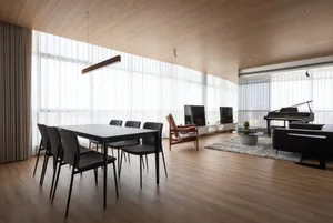Modern living room featuring a sleek, black dining table surrounded by black chairs, with a large glass window, and a grand p