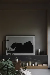 A modern living room with a large black and white abstract artwork, marble fireplace surround, and green throw blanket.
