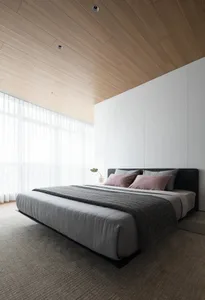 A modern minimalist bedroom with a wooden ceiling, gray bedding, and white walls.