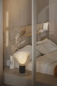 A minimalist bedroom with wooden headboard, glass nightstand, and marble vase.