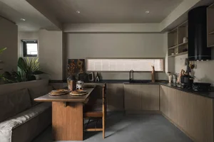A modern minimalist kitchen with dark wood cabinetry and a long table.