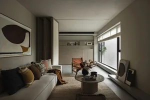 A modern minimalist living room with neutral tones, featuring a white sofa, wooden coffee table, and abstract wall art.