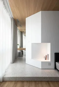 A modern minimalist living room with terrazzo flooring, white walls, and wooden ceiling.