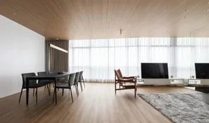 Modern minimalist living and dining room with open-concept layout and wooden elements.