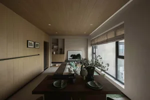 Modern residential dining area featuring a wooden table, fabric seating, and glass elements.
