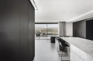 A modern residential kitchen featuring concrete countertops and glass windows with a view of the hills.