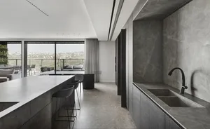 A modern residential kitchen with a marble island and concrete flooring.