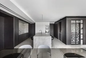 A modern residential kitchen featuring a kitchen island with a marble countertop, dark wood cabinets, and built-in wine stora