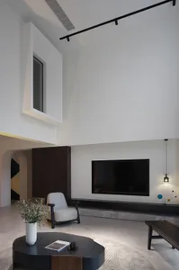 A modern split-level living room featuring concrete walls, a minimalist armchair, and a low coffee table.