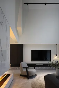 A modern living room featuring a concrete floor, minimalist design, and a single armchair in front of a television.