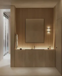 Minimalist bathroom with wooden walls featuring a large rectangular mirror and wooden vanity with integrated sink, illuminate