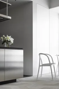Modern kitchen with sleek steel cabinets and glass interior, featuring white lilies in a vase.