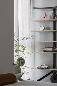 A minimalist shelf decorated with a small figurine, a round clock, a white toy car, and a metallic object.