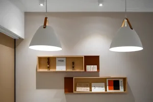 Modern home library with floating wooden shelves, illuminated by hanging pendant lights.