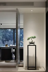 Minimalist, modern living room with metallic partition and bonsai tree on pedestal