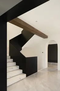 Modern staircase with black railings and marble steps.