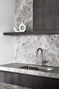 Contemporary kitchen featuring a sleek, minimalist design with dark wood cabinetry and a marble countertop and backsplash.