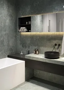 A modern minimalist bathroom featuring a white bathtub and a black countertop with a sink and a shelf with towels and toiletr