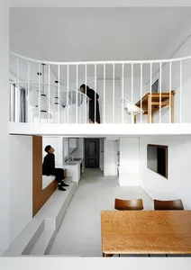 現代簡約住宅室內，白色牆面搭配木質家具，前景為木製餐桌。