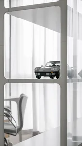 A modern office space with minimalist interior design, featuring metal shelves, glass partitions, and fabric curtains.
