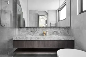 Modern residential bathroom featuring marble countertops and a glass-enclosed shower.