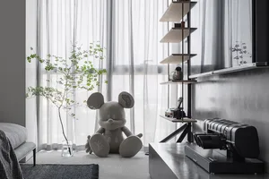 A modern, urban living room featuring a plush Mickey Mouse toy, a sleek, minimalist entertainment unit with shelves, and a co